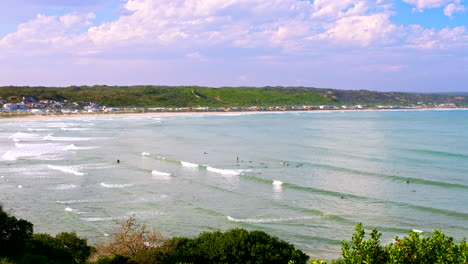 Vista-De-Teleobjetivo-De-Alto-ángulo-De-Surfistas-Que-Intentan-Atrapar-Olas-En-La-Bahía-Tranquila