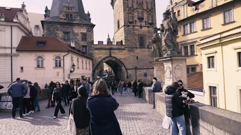 Charles-Bridge-medieval-stone-bridge-in-Prague,-Czech-Republic,-tilt-up,-pidgeon-flying