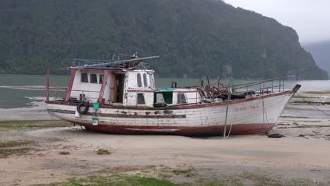 Old-Fishing-Boat-Stranded-on-Shore-of-Caleta-Tortel-Municipality,-Chile