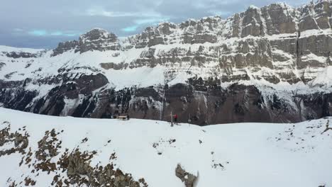 Un-Dron-Rodea-A-Dos-Personas-Paradas-En-La-Cima-De-Una-Montaña-Cerca-De-Una-Cruz.