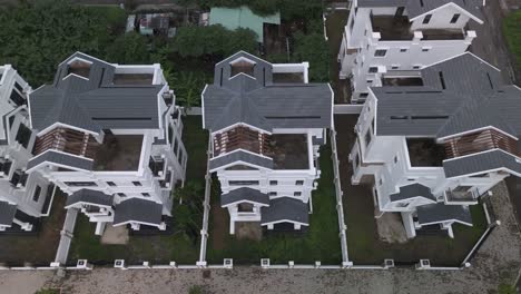 A-newly-constructed-row-of-identical-large-white-multi-story-villa-styled-houses-along-a-suburban-road