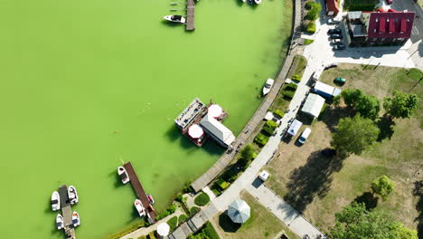 op-down-aerial-view-of-a-marina-and-boats-docked-on-the-green-waters-of-a-lake-in-Ryn,-Warmia-Masuria