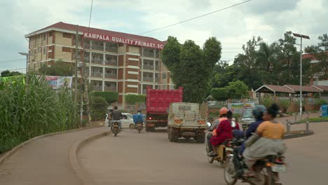 Vehicles-On-Street-And-Kampala-Quality-Primary-School-During-Daytime-In-Kampala,-Uganda