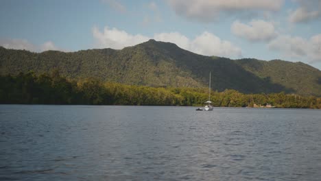 Sailboat-cruising-on-the-Daintree-River-with-mountains-and-jungle,-in-the-Daintree-Rainforest-of-Australia