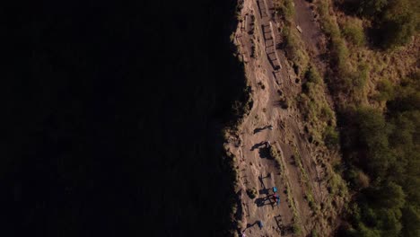 Top-down-view-of-the-path-up-to-the-Mount-Batur-on-a-a-sunny-day-in-slow-motion-with-people-walking,-copy-space-on-the-shadow-hillside