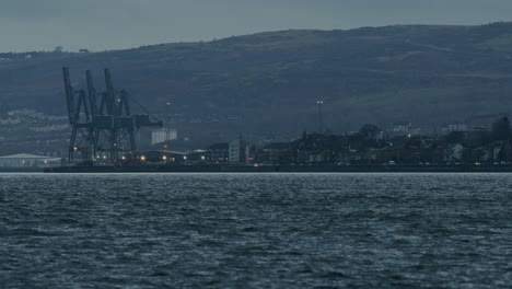 Industriehafen-Mit-Kränen-In-Der-Abenddämmerung-Mit-Plätscherndem-Wasser-Im-Vordergrund