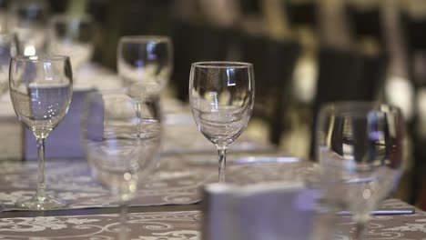 An-elegant-restaurant-with-numerous-tables-set,-featuring-chairs-and-wine-glasses-ready