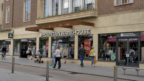 Exterior-facade-of-Mountain-Warehouse-store-with-shoppers-and-sale-signs,-Exeter-Devon-UK,-June-2024