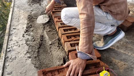 Close-up-of-industrial-bricklayer-installing-bricks-on-construction-site