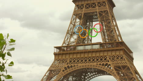 The-Eiffel-Tower-stands-tall,-its-iconic-structure-adorned-with-the-Olympic-rings,-a-symbol-of-the-upcoming-Summer-Games