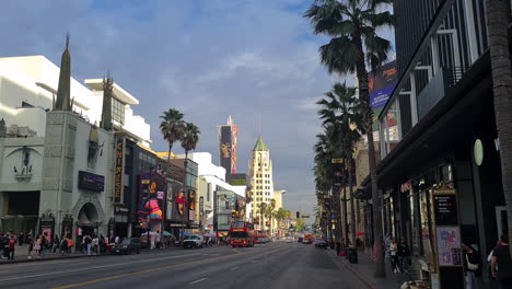 Evening-Traffic-on-Hollywood-Boulevard,-Walk-of-Fame-Sidewalk,-Buildings-and-People,-Los-Angeles,-California-USA