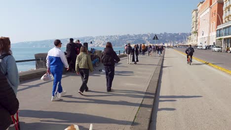 People-walking-at-Via-Partenope-street-on-a-sunny-winter-day-in-Naples,-Italy