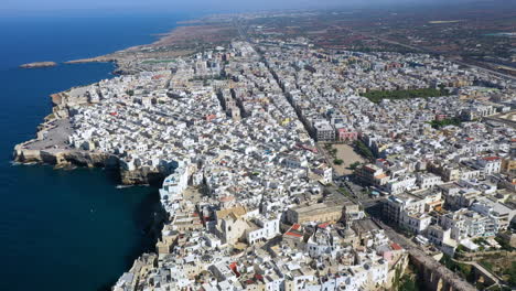 Slow-aerial-revealing-shot-of-Polignano-a-Mare's-cliffside-beauty-in-Puglia,-Italy