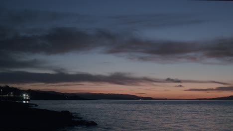 Sereno-Crepúsculo-Sobre-Tranquilas-Aguas-Costeras-Con-Siluetas-De-Paisaje