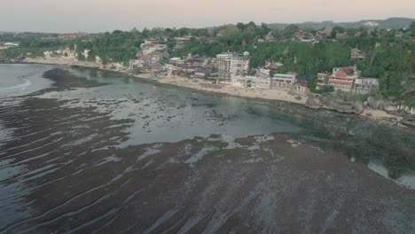 Weit-Entfernte-Drohnenaufnahme-Der-Gebäude-Am-Strand-Von-Bingin-Bei-Sonnenuntergang-Und-Ebbe-In-Uluwatu,-Bali,-Indonesien