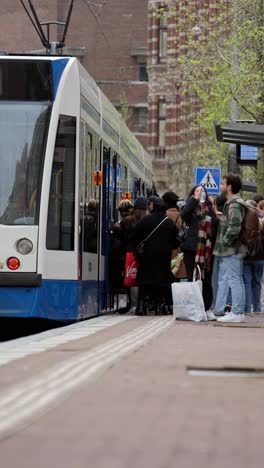 Menschen-Steigen-In-Die-Niederländische-Straßenbahn-In-Der-Hauptstadt-Amsterdam-Ein,-Offene-Türen-Am-Bahnsteig,-öffentliche-Verkehrsmittel-In-Den-Niederlanden