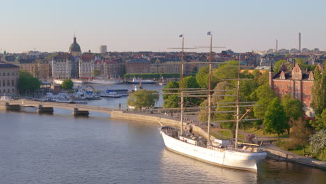 Barco-Que-Actúa-Como-Albergue-Juvenil-Amarrado-En-El-Banco-De-Skeppsholmen-En-Estocolmo,-Aéreo