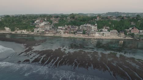 Pulling-away-Drone-shot-of-Bingin-Beach-buildings-at-sunset-and-low-tide-in-Uluwatu-Bali-Indonesia