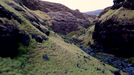 Low-altitude-drone-flight-over-black-volcanic-rocks-in-a-Maui-canyon,-Hawaii