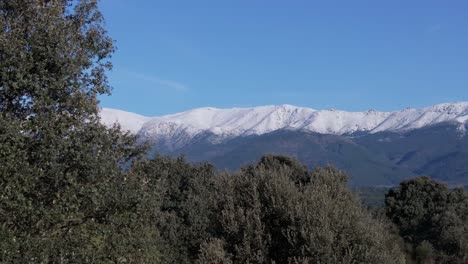 Seitlicher-Flug-Mit-Drohne-Im-Tiétar-Tal,-Wo-Wir-Den-Faszinierenden-Wald-Sehen,-Den-Das-Tal-Hat,-Es-Gibt-Baumkronen-Und-Im-Hintergrund-Die-Berge-Mit-Ihren-Schneebedeckten-Gipfeln