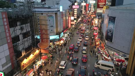 Antena-De-Yaowarat-Road-En-El-Distrito-De-Chinatown-Iluminada-Por-La-Noche-Con-Letreros-De-Neón-Y-Puestos-De-Vendedores-Ambulantes-De-Comida-Para-Peatones-Y-Tráfico,-Famoso-Monumento