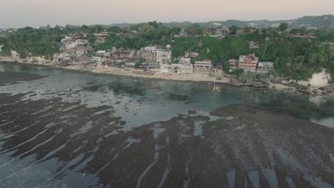 Medium-Panning-Drone-shot-of-Bingin-Beach-buildings-at-sunset-and-low-tide-in-Uluwatu-Bali-Indonesia