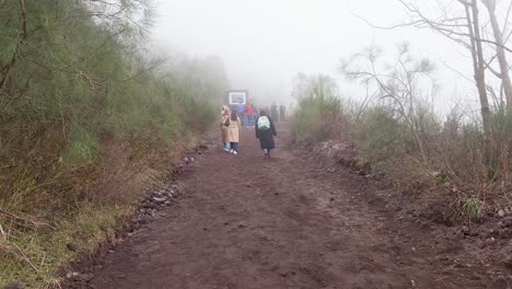 Tourists-hiking-along-misty-edge-of-active-volcano-crater-of-Mount-Vesuvius---Naples,-Italy