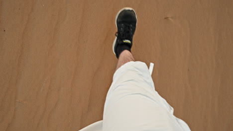 Person-walking-on-sandy-beach,-view-of-feet-in-motion