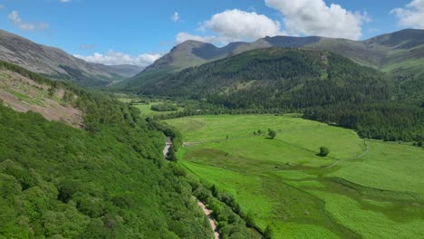 Wide-green-valley-surrounded-by-forested-hills-and-mountains