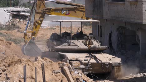 Israeli-Merkava-tank-advancing-as-excavator-follows-behind-clearing-debris-for-other-vehicles