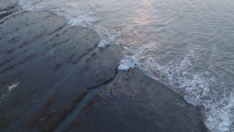 Slowly-Descending-Drone-shot-of-Bingin-Beach-low-tide-reef-and-waves-at-sunset-in-Uluwatu-Bali-Indonesia