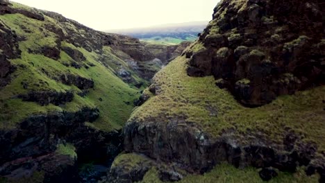 Dolly-in-ascending-drone-flight-between-two-ridges-reveals-stunning-canyon-and-mountain-landscape-in-Maui,-Hawaii