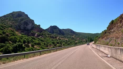 Journeying-across-idyllic-countryside,-road-weaves-between-emerald-hills