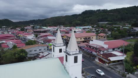 Aerial-view-of-Boquete-town-showcasing-church-spires,-buildings,-and-surrounding-hills