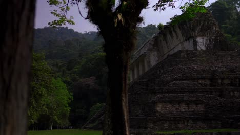 Panning-reveal-shot-through-trees-of-The-Great-Palace-ruin-at-Palenque-Chiapas-Mexico-Mayan-civilization