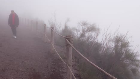 Tourist-hiking-along-misty-edge-of-active-volcano-crater-of-Mount-Vesuvius---Naples,-Italy