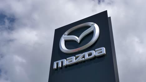 Mazda-Logo-Auf-Einem-Schild-Mit-Bewölktem-Himmel-Im-Hintergrund,-Exeter,-Devon,-Großbritannien,-Juni-2024