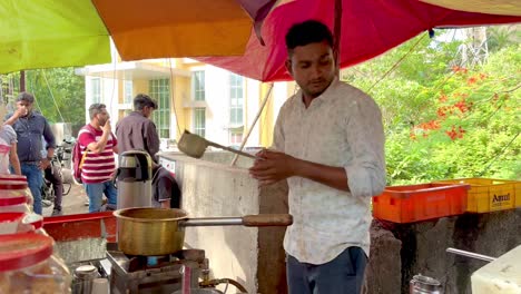 Indian-roadside-tea-stall-with-tea-in-preparation-as-people-smoke,-chat,-and-enjoy-their-chai