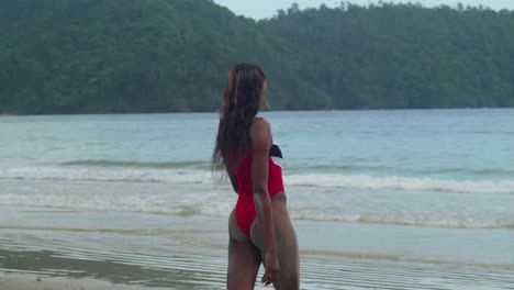 A-young-girl-in-a-bikini-on-Trinidad's-tropical-island-beach-walking-into-the-ocean