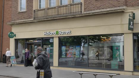 Exterior-facade-of-Holland-and-Barrett-store-with-shoppers,-Exeter-Devon-UK,-June-2024