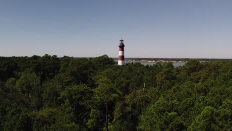 Aerial-dolly-to-red-and-white-banded-lighthouse-in-national-wildlife-refuge-Chincoteague-Island-Virginia,-slow-motion