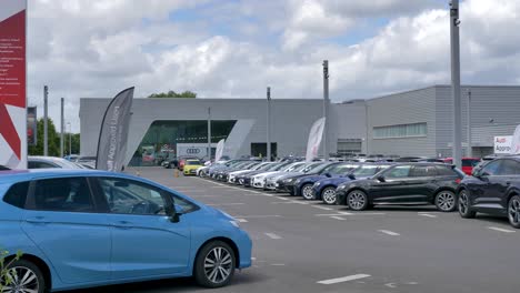 Exterior-of-Audi-dealership-with-flags-blowing-in-the-wind,-Exeter,-Devon,-UK,-June-2024