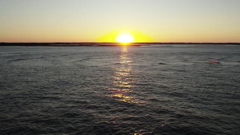 Aerial-dolly-to-serene-seascape-with-sunset-beam-ray-of-golden-light-crossing-water,-Chincoteague-Island-Virginia,-slow-motion