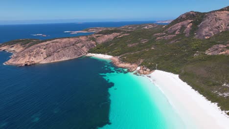 4K-Drone-video-panning-sideways-revealing-the-crystal-clear-turquoise-ocean-merging-into-the-dark-blue-hues-of-Thistle-Cove-Beach-in-Esperance,-Western-Australia