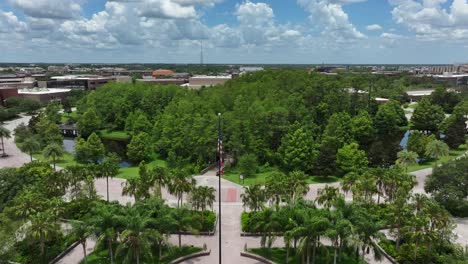 Aerial-flyover-american-flag-with-green-trees-between-river-during-sunny-day