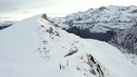 Un-Dron-Rodea-A-Dos-Personas-Paradas-En-La-Cima-De-Una-Montaña-Cerca-De-Una-Cruz.