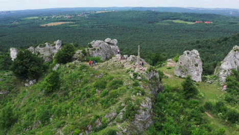 Aerial-view-of-tourists-sightseeing-Zborow-Mountain-climbing-area-surrounded-by-lush-green-forest