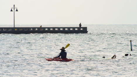 Ocean-Swimmers-Follow-Kayak-Near-Pier-in-Key-West,-Florida,-USA