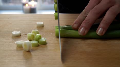 Weibliche-Hände-Schneiden-Frische-Frühlingszwiebeln-Auf-Einem-Hölzernen-Schneidebrett