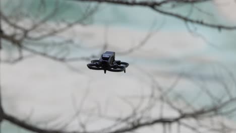 Schwarze-Quadrocopter-Drohne-Fliegt-In-Der-Luft-Mit-Verschwommenem-Baum-Im-Hintergrund